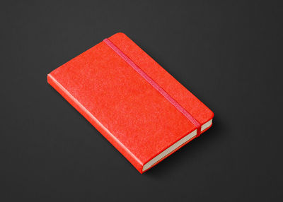 Close-up of red open book on table against black background