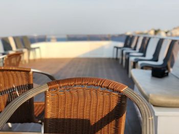 Empty chairs and table at beach against sky