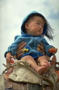 Cute girl looking away while sitting on wall