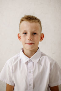 Portrait of boy standing against wall