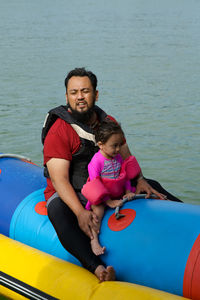 Father and son sitting on boat in lake