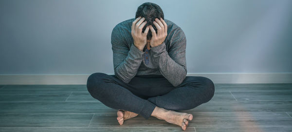 Low section of woman sitting on hardwood floor at home