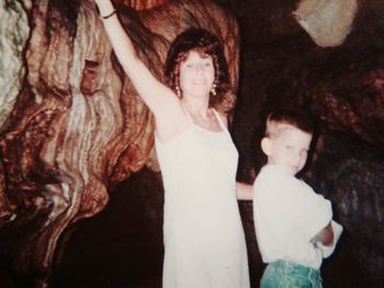 Side view of woman standing by tree trunk