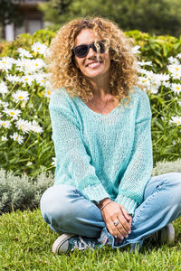 Portrait of woman wearing sunglasses sitting on grassy land
