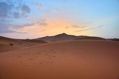 Scenic view of sand dunes against sky during sunset