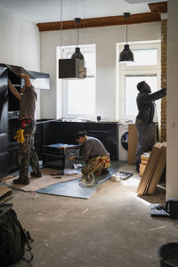 Multiracial male and female carpenters working in kitchen at home