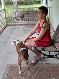 Young woman with dog sitting at porch