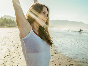 Woman with arms raised while standing on beach