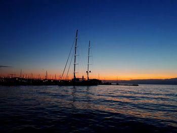 Silhouette sailboats in sea against clear sky during sunset