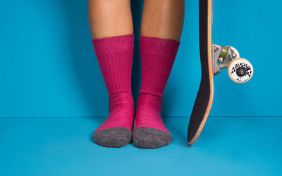 Low section of woman standing against blue background