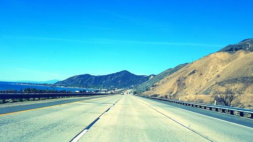 Road by mountain against clear blue sky