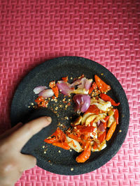 High angle view of hand grinding chilli, garlic, and shallot to make sambal.