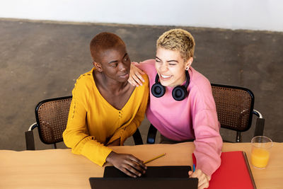 High angle view of smiling lesbian couple using laptop on table at home