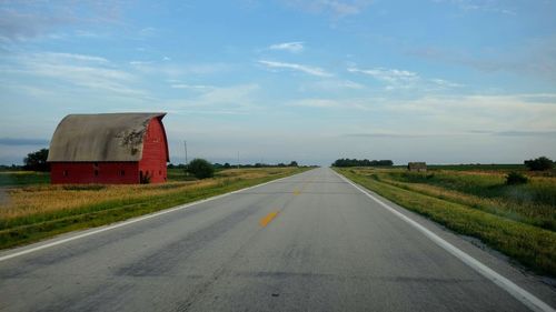 Road amidst field against sky