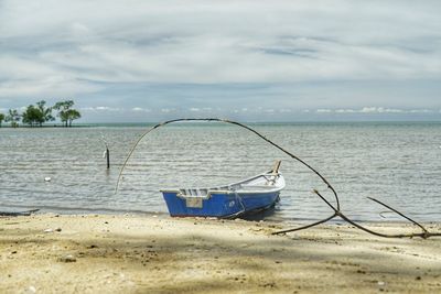 Boat moored on beach against sky