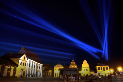 Illuminated buildings against blue sky at night