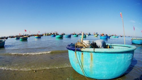 Boats moored in sea against clear blue sky