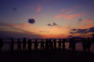 Silhouette people at beach against sky during sunset