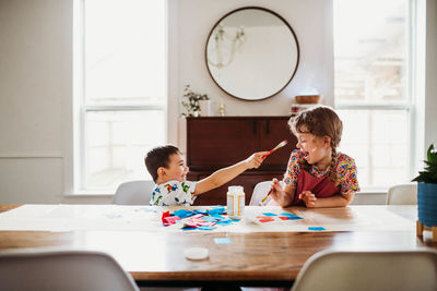 Young brother and sister doing arts and crafts at home in spring