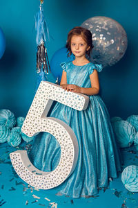 Girl in the blue dress in the studio with the balloon and with the number five