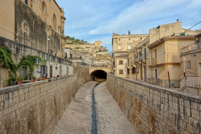 Rear view of people walking on street amidst buildings