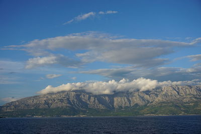 Scenic view of sea by mountain against sky