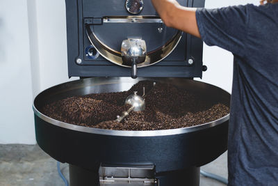 Midsection of preparing roasted coffee beans in machinery