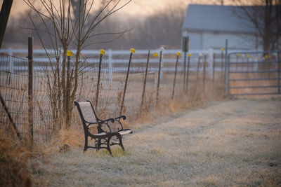 Empty chairs and table on field by building