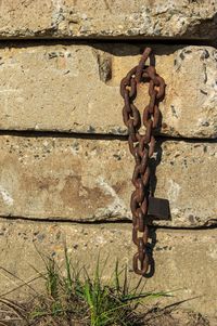 Close-up of rusty chain against wall