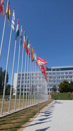 Low angle view of flags against clear blue sky