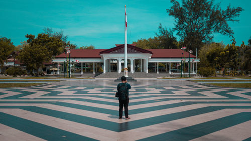 Rear view of man standing by building against sky