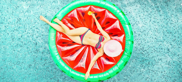 Directly above shot of woman lying on inflatable raft over swimming pool
