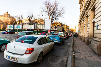 Cars on road by buildings in city against sky