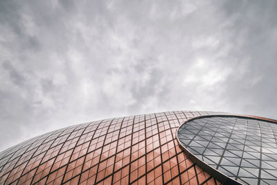 Low angle view of modern building against cloudy sky