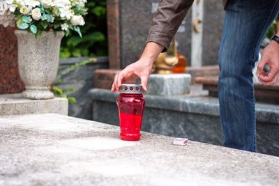 Midsection of man lighting candle in cemetery