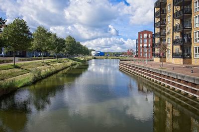 Canal amidst buildings in city against sky