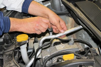 Cropped hands repairing car engine