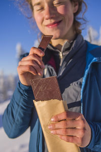 Young woman smiling and eating chocolate in the sun
