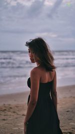 Woman standing on beach against sky