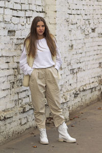 Portrait of young woman standing against brick wall