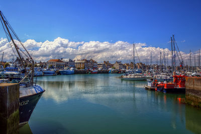 Sailboats moored at harbor against sky