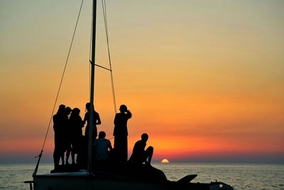 Silhouette of people in sea at sunset