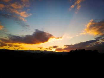 Silhouette landscape against dramatic sky during sunset