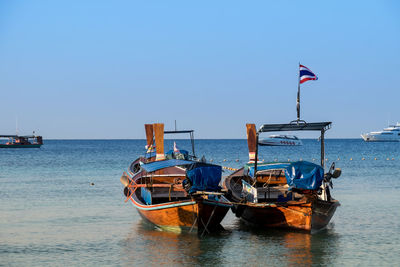 Boats moored at river against clear sky