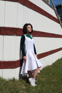 Young woman with eyes closed standing by wall on grassy field during sunny day