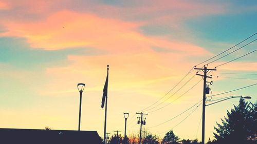 Low angle view of electricity pylon against sky during sunset