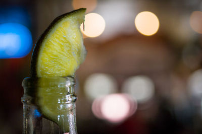 Close-up of lime in beer bottle against defocused lights at night