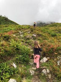 Rear view of girl following mother hiking on mountain