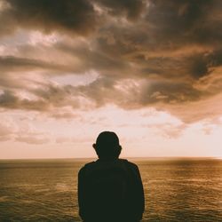 Rear view of silhouette man looking at sea against sky