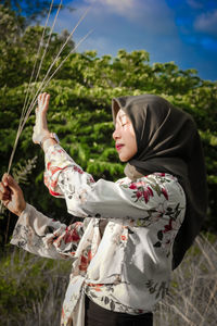 Side view of woman holding umbrella on field